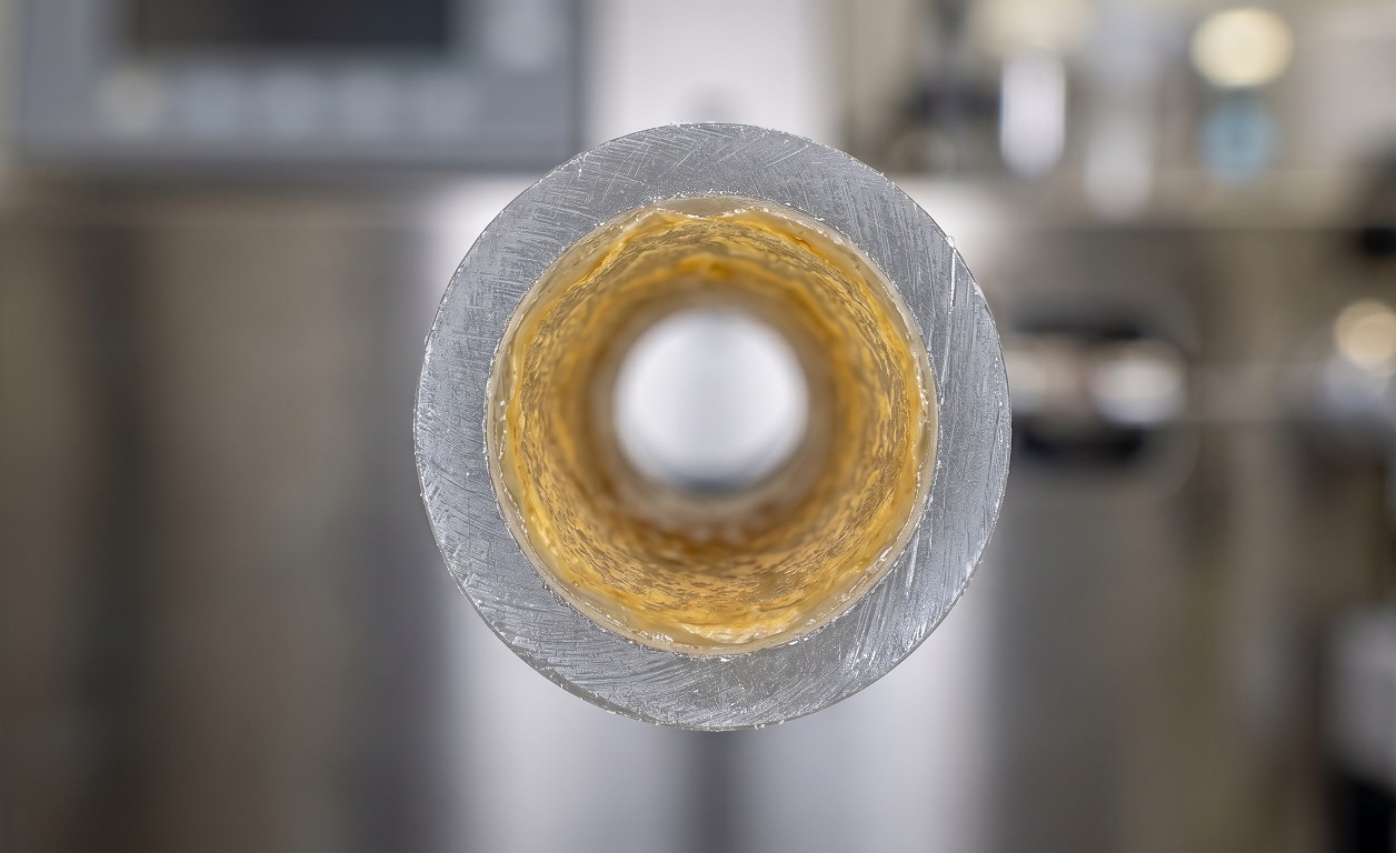 Cross-section illustration of a biofilm-coated water tubing manifold inside a clinical chemistry analyzer