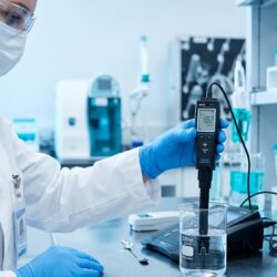 A scientist testing clinical laboratory water purity using a resistivity meter in a modern medical laboratory