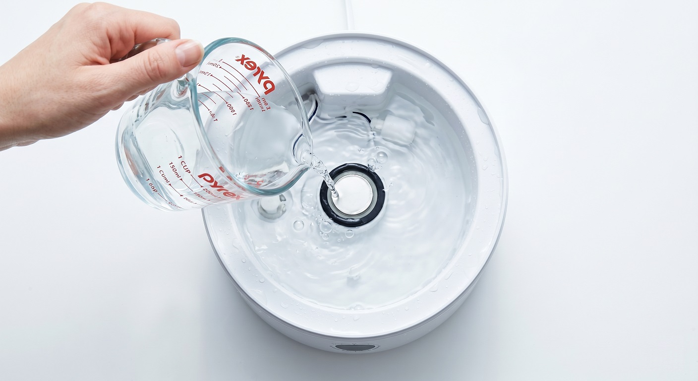 White vinegar solution being poured onto an ultrasonic humidifier transducer disc inside the base reservoir